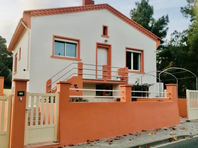 Maison à façade blanche, encadrements de fenêtres, escalier et muret de clôture orange terre cuite